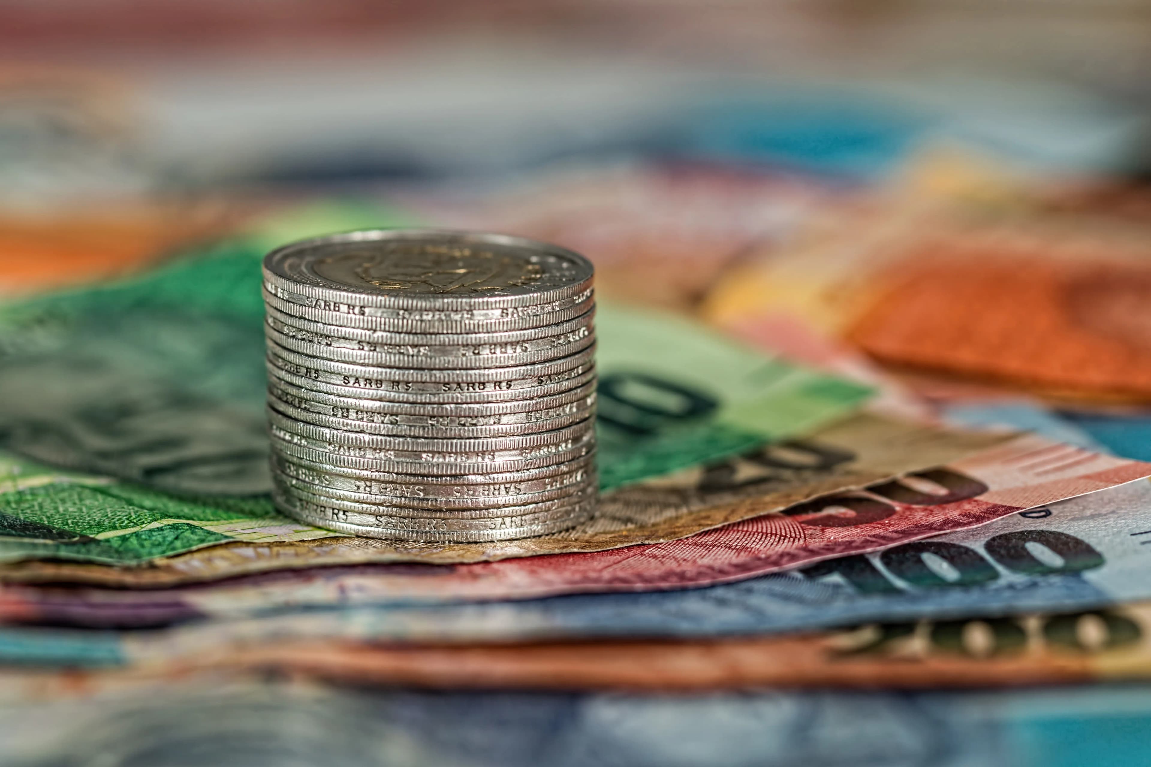 A stack of coins on banknotes, representing Dividend Aristocrats and growing dividend income