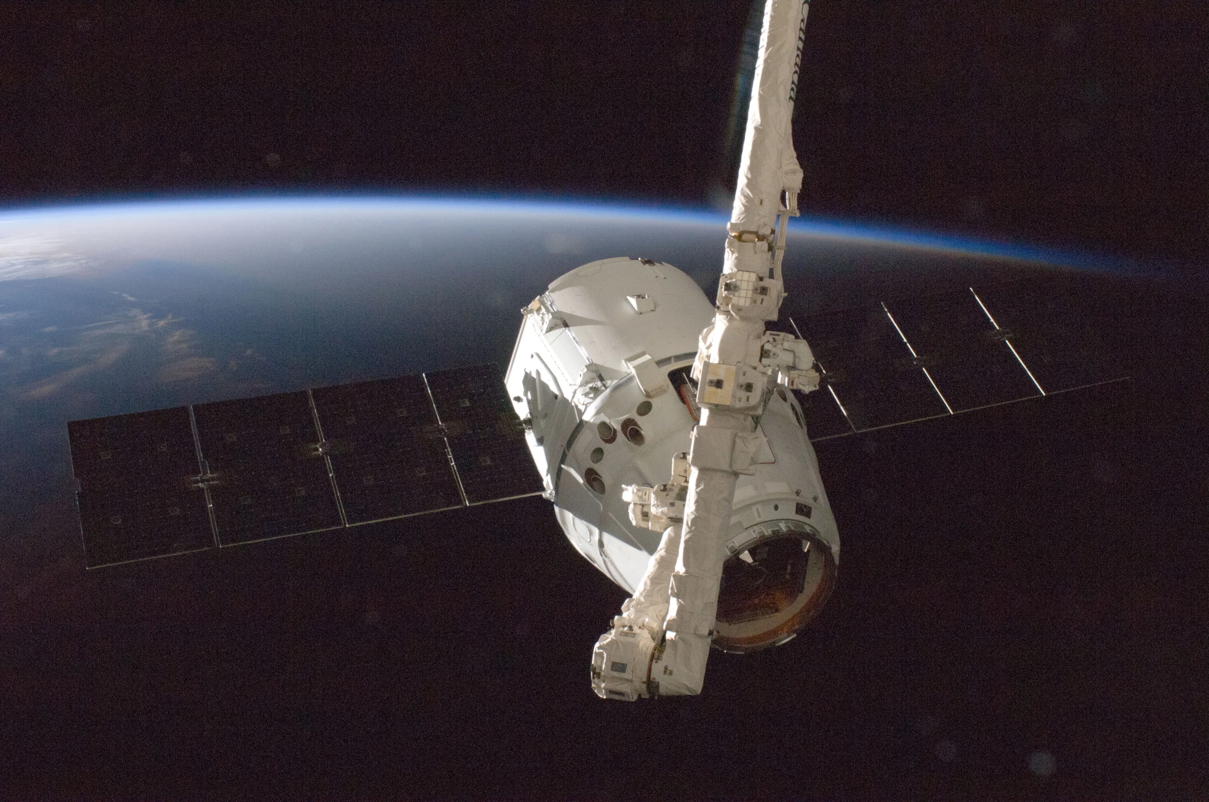 A spacecraft with solar panels in orbit above Earth, representing SpaceX Starship and Starlink