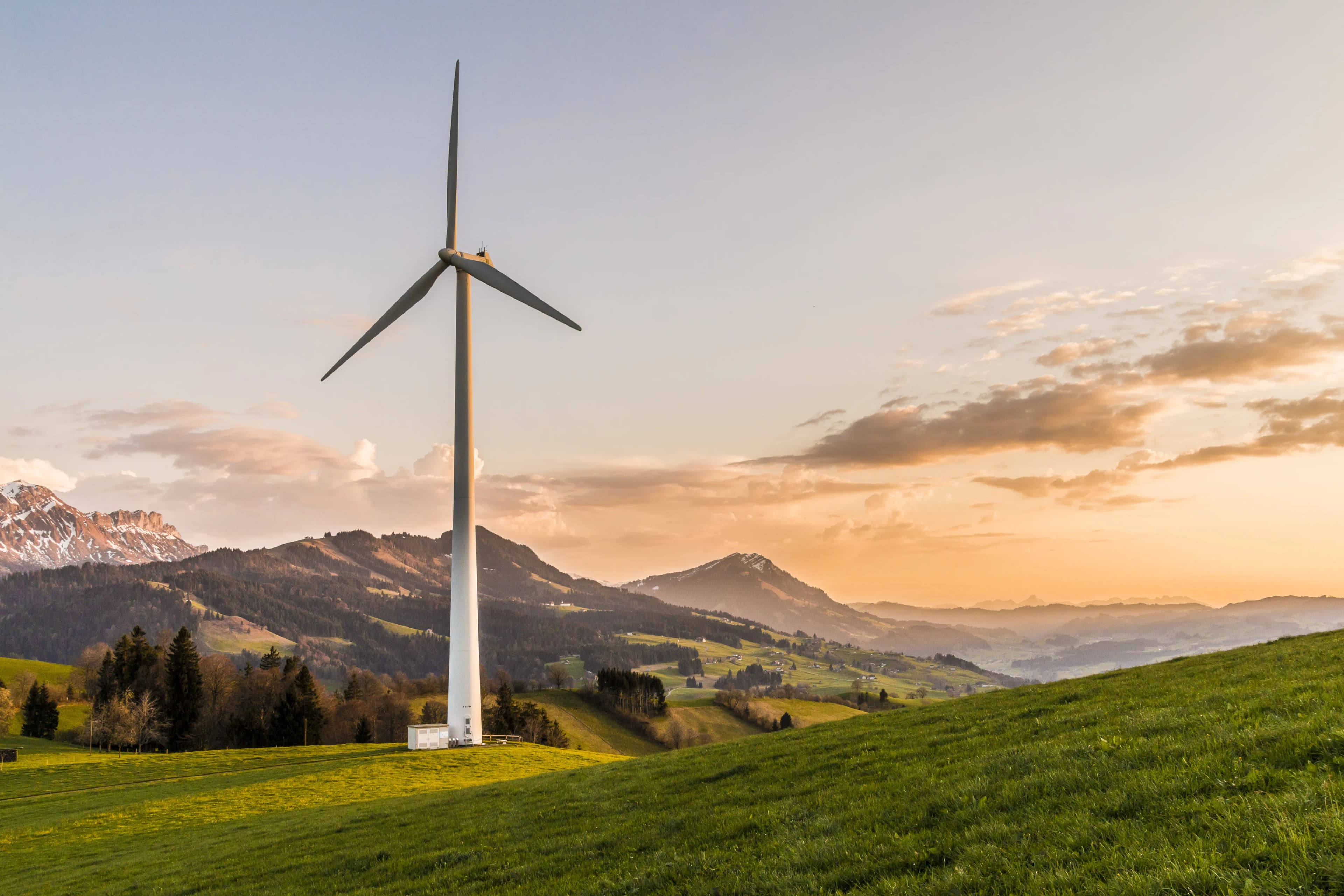 A wind turbine at sunset representing clean energy investment to power AI data centers