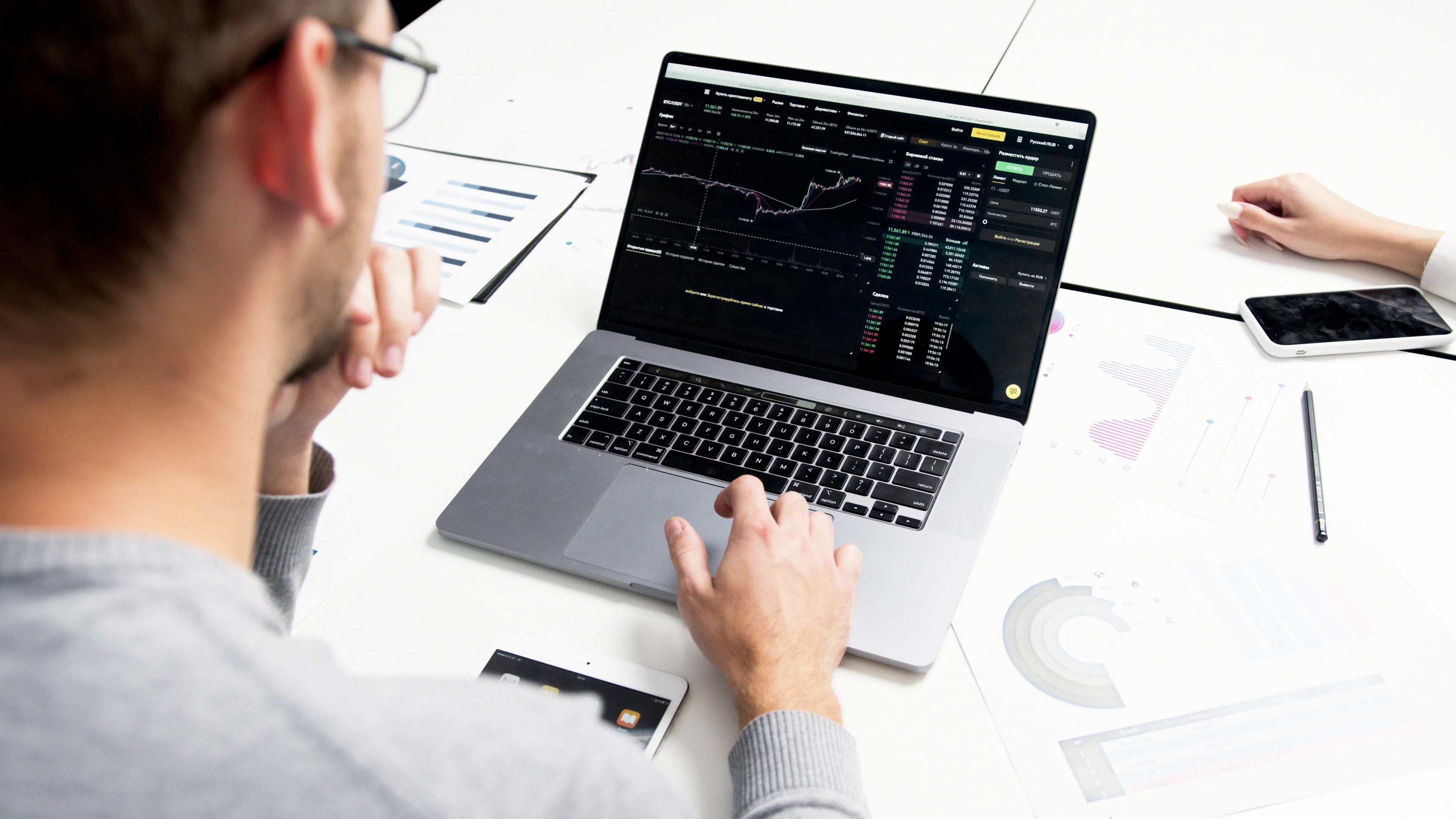 A person analyzing charts and a pie chart on a desk, representing portfolio diversification