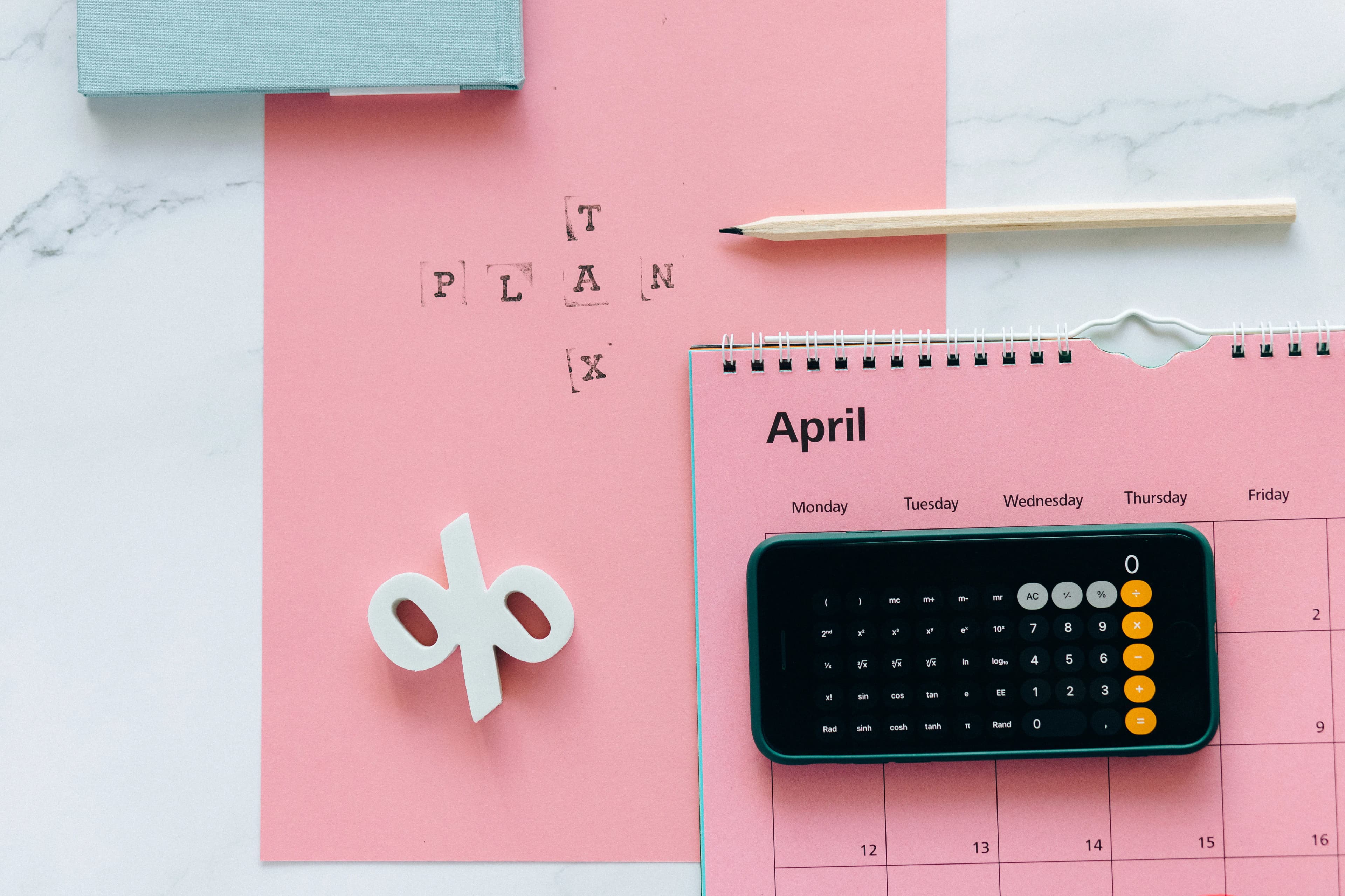 A financial planning flat lay with a percent symbol and calendar, representing Roth vs Traditional IRA