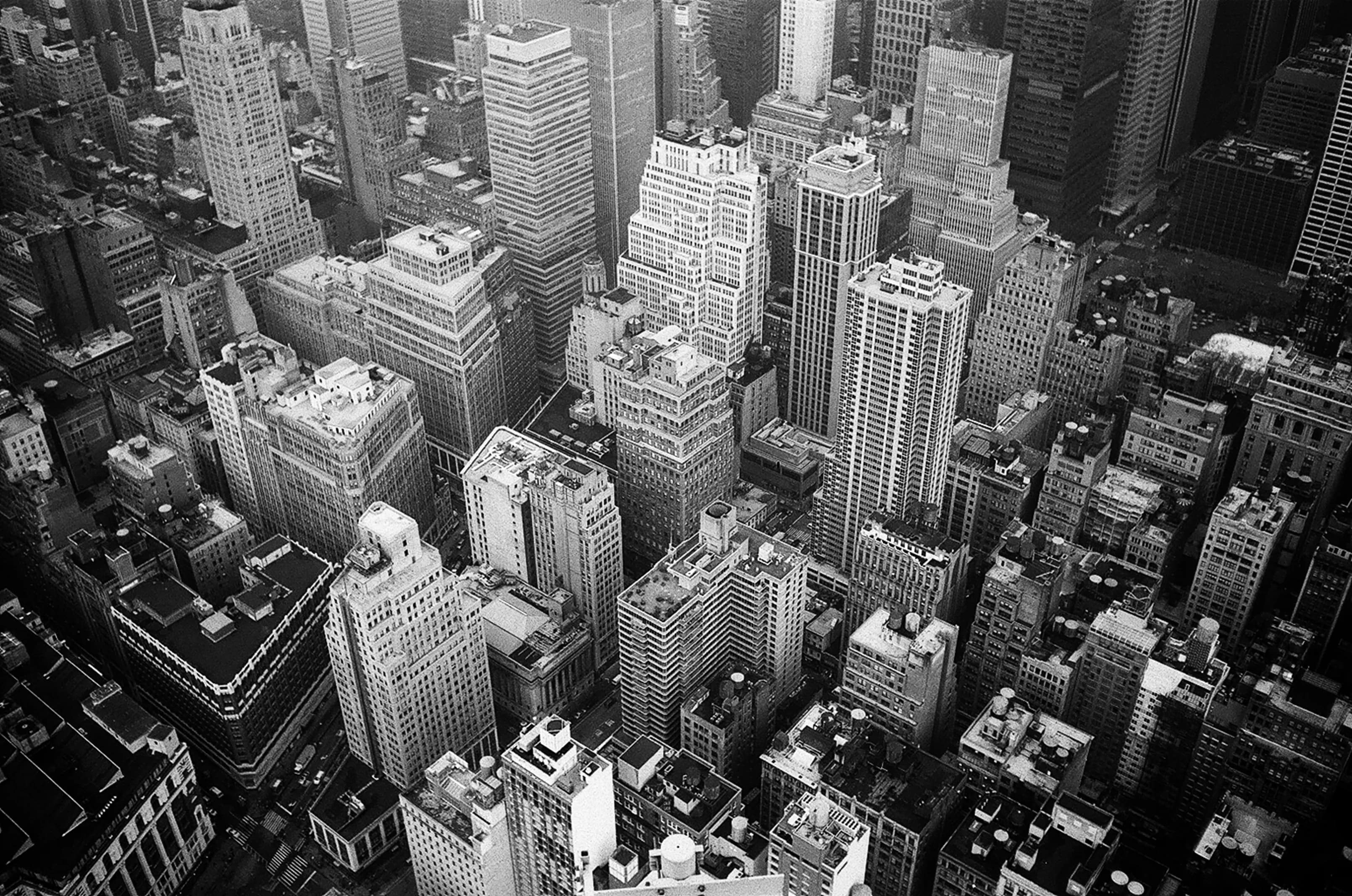 A black and white aerial view of the New York City skyline, representing Wall Street and the US market