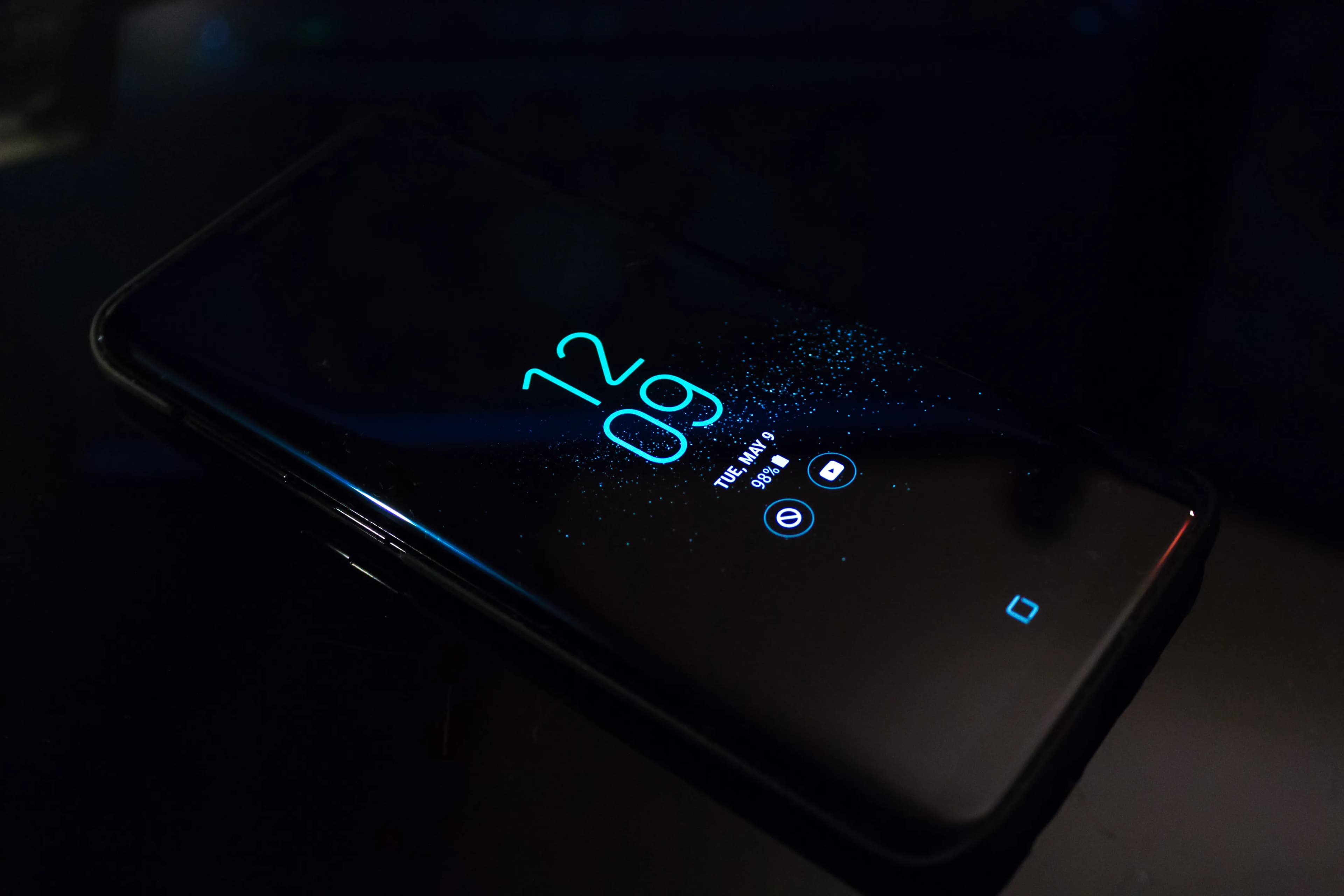 A modern smartphone with a glowing display on a dark surface, representing Apples new iPhone lineup